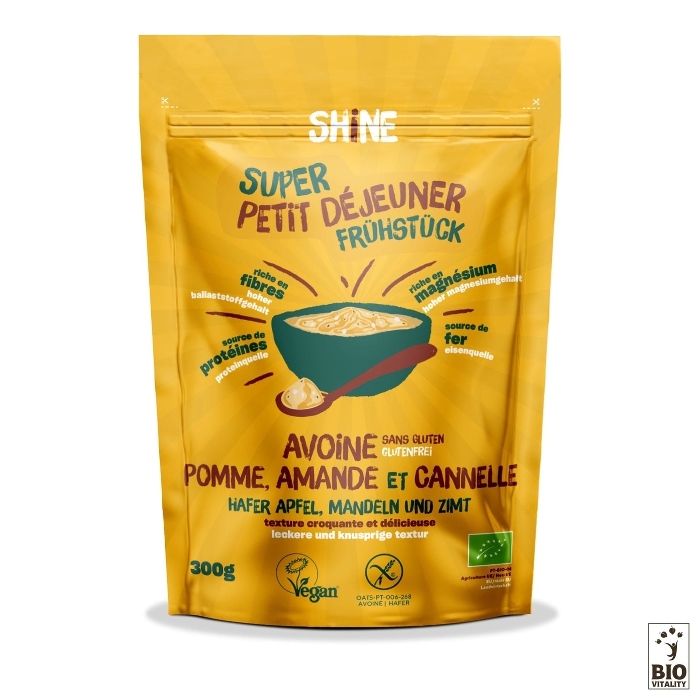 Lemballage jaune des céréales Avoine Pomme, Amande et Cannelle Bio de SHINE met en valeur la pomme, lamande et la cannelle. Elles sont sans gluten, végétaliennes, biologiques et bilingues en français et en allemand. Profitez de la richesse du beurre damande à chaque bouchée !.
