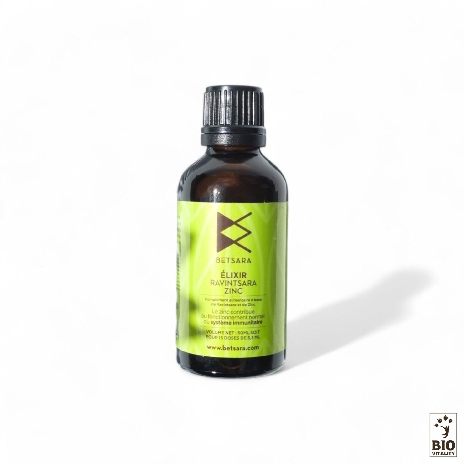 Le petit flacon foncé à létiquette verte porte linscription Lélixir au ravintsara et au zinc - 50ml de BETSARA, soulignant ainsi son rôle de complément alimentaire. Le logo Biovitality apparaît dans le coin inférieur droit et le flacon projette une ombre subtile sur le fond blanc.