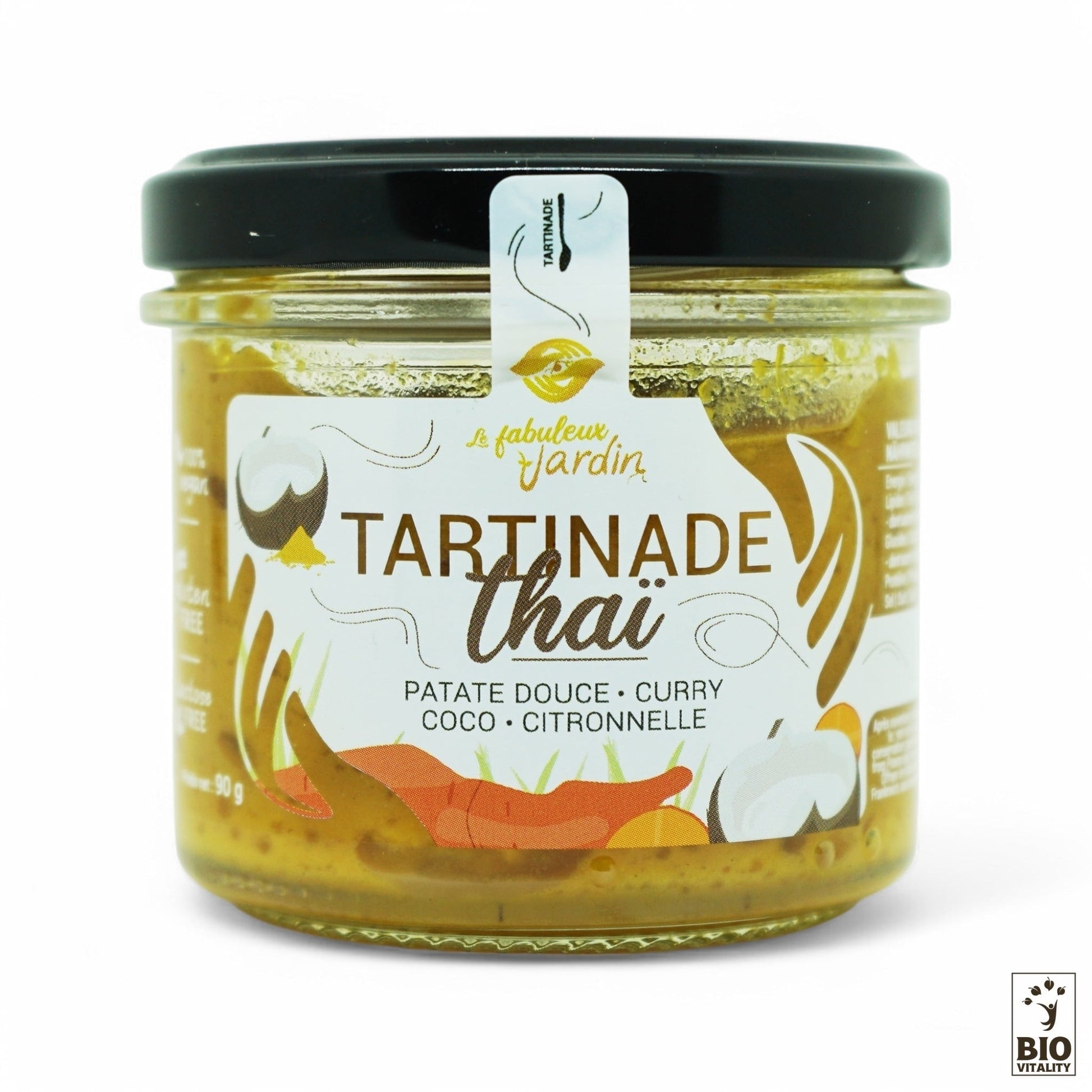 Le pot de Tartinade Thaï Bio - 90g de FABULEUX JARDIN propose des saveurs exotiques à base de patate douce, curry, noix de coco et citronnelle. Cette pâte à tartiner végétalienne et sans gluten est dotée dun couvercle noir et dune étiquette blanche présentant des illustrations dingrédients.