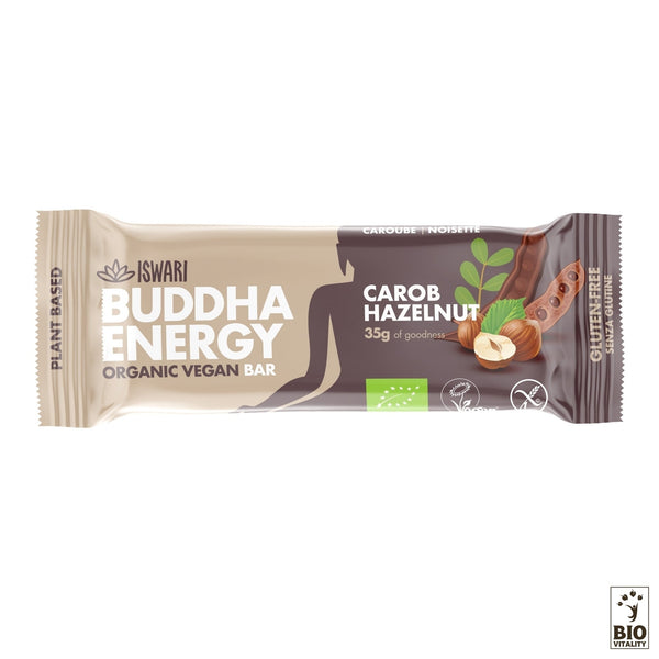 La Buddha Energy Bar Caroube Noisettes Bio dISWARI présente un emballage présentant des images vibrantes de noisettes et de caroubes, étiquetées végétaliennes avec des icônes dorigine végétale et sans gluten, ce qui la rend idéale pour les régimes végétaliens à la recherche de barres énergétiques nutritives.