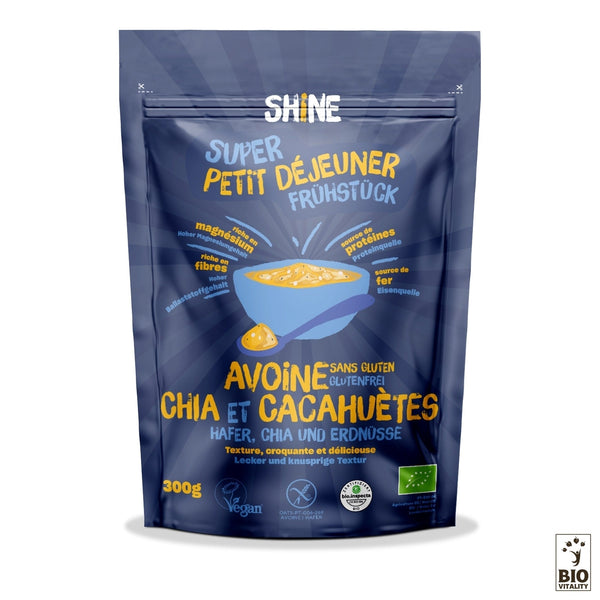 Lemballage bleu de lavoine chia et cacahuète bio de SHINE - 300 g contient des flocons davoine, des graines de chia et des cacahuètes. Les étiquettes mettent en avant les attributs végétaliens, sans gluten et biologiques pour un petit-déjeuner équilibré avec des avantages nutritionnels dans plusieurs langues.